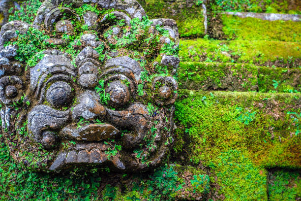istock moss covered Balinese god face stone statue 696325634