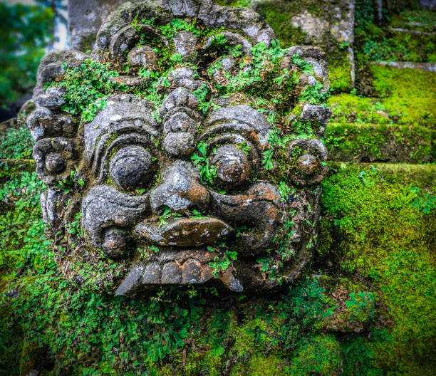 istock moss covered Balinese god face stone statue 696325644