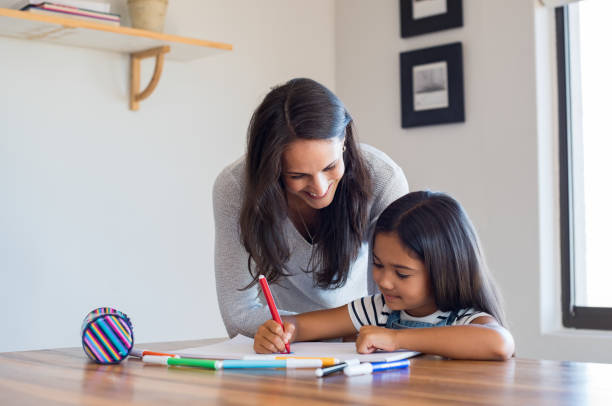 Mother helping daughter draw Happy mother and smiling daughter together painting using markers. Mother helping adopted child with art homework. Cheerful mother and asian little girl making painting at home. homework stock pictures, royalty-free photos & images