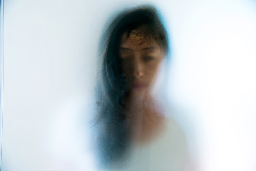 Woman face peering through frosted glass