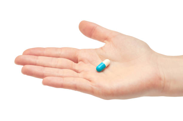 istock Beautiful female hand holds pill gesture. Isolated on white background 696334154