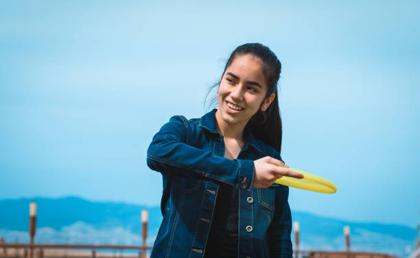 istock Young girl throwing yellow frisbee 696337986