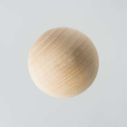 Surreal design concept - real wooden ball float on grey background like the planet on the universe