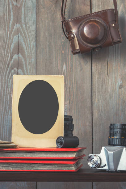 Old frame for photos, photo albums and equipment Old photo frame, red photo albums, old camera and hanging leather case old black leather photo album stock pictures, royalty-free photos & images