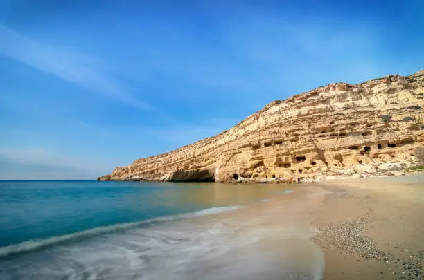 Panorama of Matala beach with caves on the rocks that were used as a roman cemetery and at the decade of 70's were living hippies from all over the world, Crete, Greece