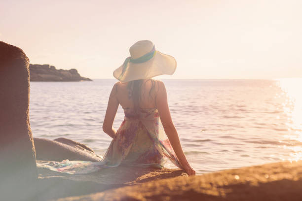 istock Women is sitting on a rock on the beach 696360928