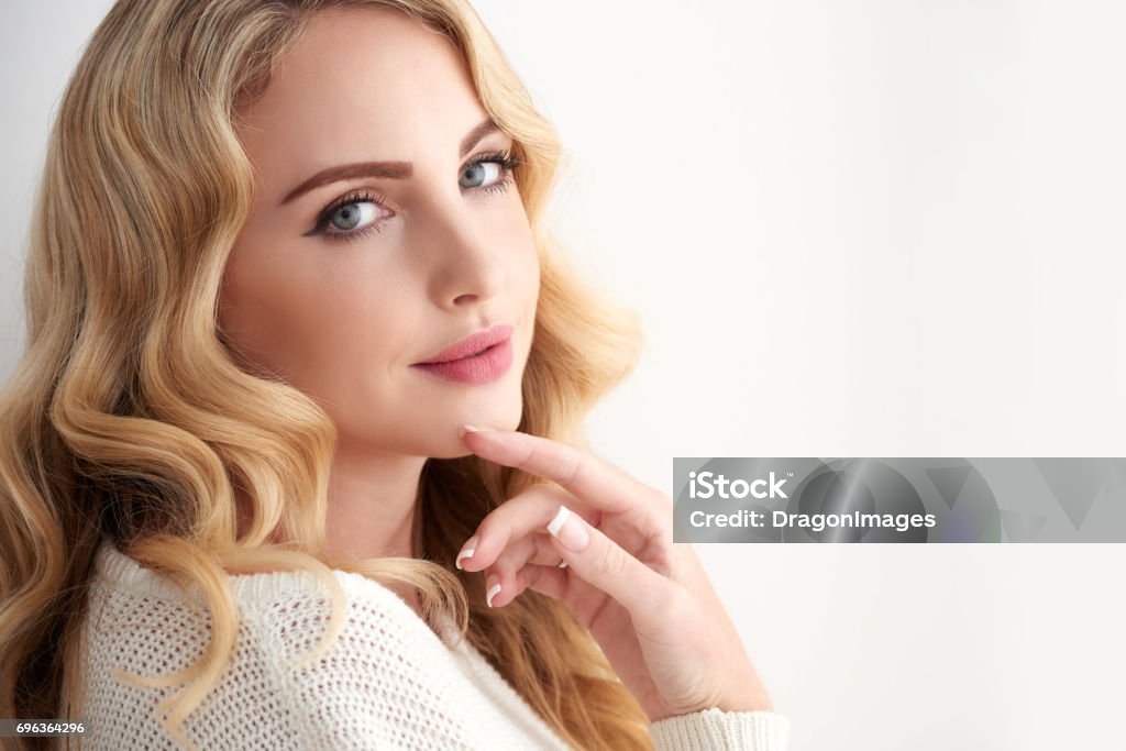 Perfect Blond Beauty Portrait of gorgeous young woman with wavy blond hair posing elegantly looking at camera Beautiful Woman Stock Photo