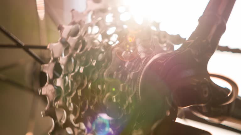 Close-up of bicycle wheel spoke, gear and chain in motion with lens flare