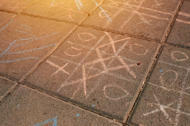 Strategic game of tic tac toe played on street pavement, selective focus