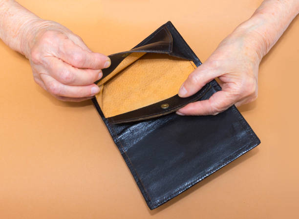 istock Senior woman sitting on window sill with empty purse, closeup. 696371914
