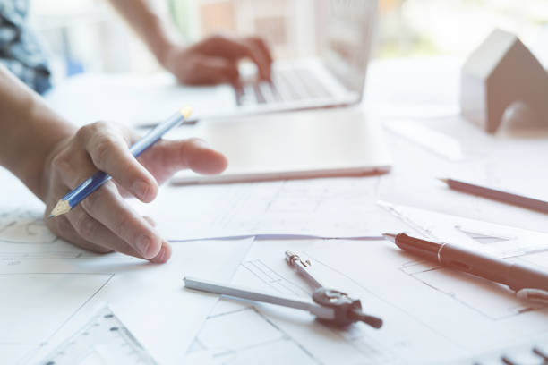 istock Architect working on real estate project at workplace. Male engineer hand working with living house blueprint at office. Business, people, construction and building concept 696373852