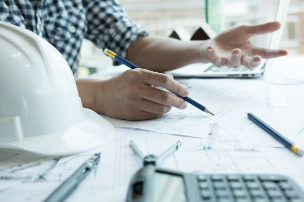 istock Architect working on real estate project at workplace. Male engineer hand working with living house blueprint at office. Business, people, construction and building concept 696373864