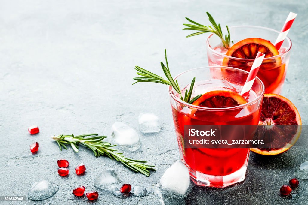 Red cocktail with blood orange and pomegranate. Refreshing summer drink on gray stone or concrete background. Holiday aperitif for Christmas party. Christmas Stock Photo