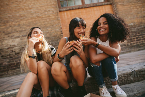 istock Young friends sitting on the sidewalk and having pizza 696384068