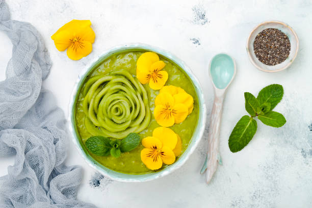 frühstück detox grünen smoothie schüssel garniert mit kiwi rose und essbare stiefmütterchen blüten. overhead, top aussicht, flach zu legen - flower cabbage kale edible flower stock-fotos und bilder