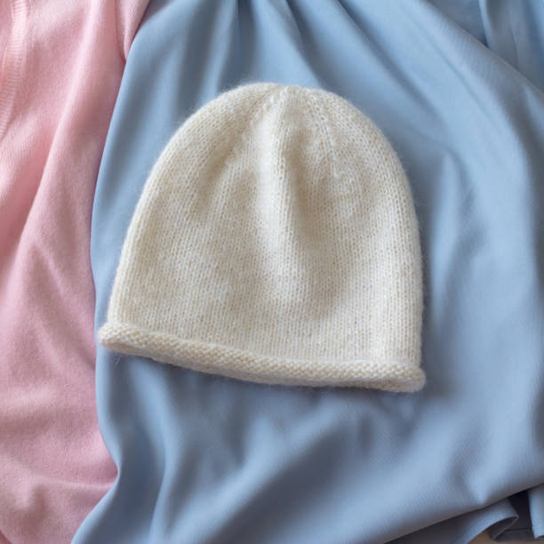 istock Hat white knitted on the needles lies on blue material with pink 696384462