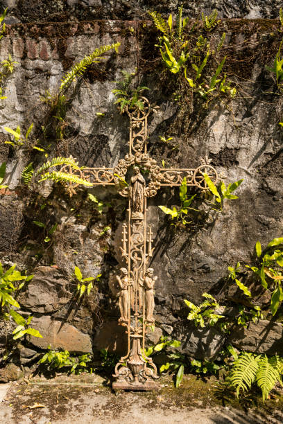 старое ржавое распятие, прикрепленное к старой каменной стене - old cross shape stone weathered стоковые фото и изображения