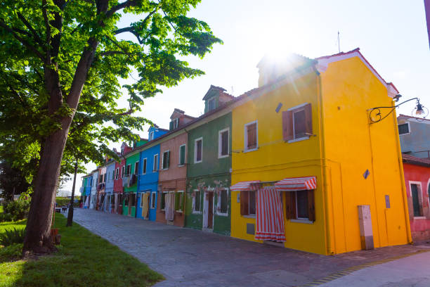 Burano, Italy- January, 06: Italian elderly man sitting outside his house next his bicycle, behind the colorful houses of Burano island on January 06, 2022