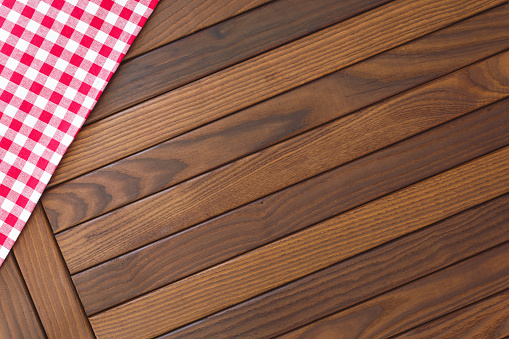 Wooden background with red and white checkered tablecloth. Top view, blank space