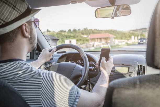 istock Man using smartphone during car drive. Dangerous driving concept. 696418810