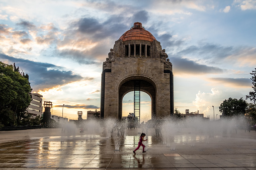 Mexico City, Mexico - Nov 2016: Girl playing with the water fountain in front of Monument to the Mexican Revolution (Monumento a la Revolucion) - Mexico City, Mexico