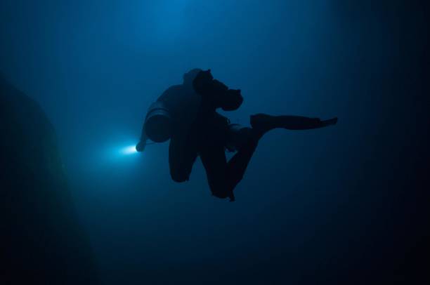 istock tech diver with two tanks in blue cloudy water with flashlight tech diving 696426894