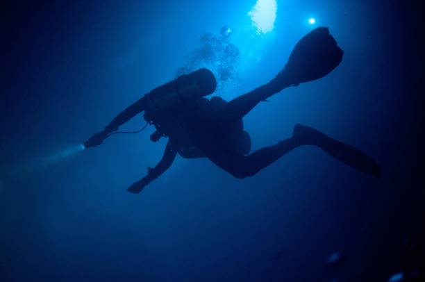 tech diver with two tanks in blue cloudy water with flashlight tech diving 2