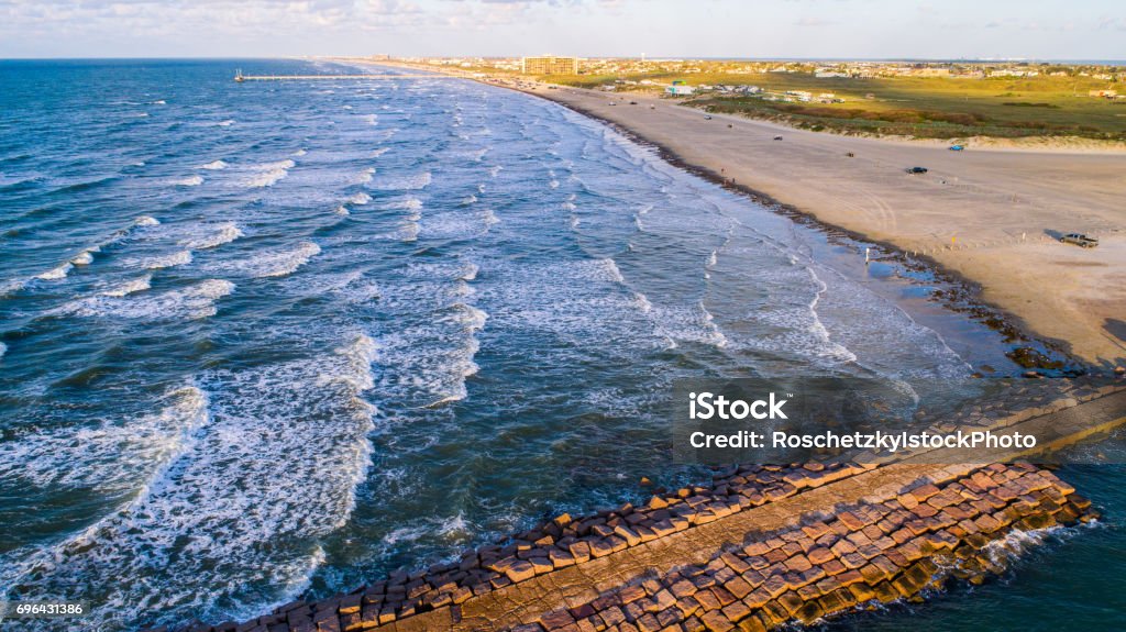 Padre Island Paradise Nature Escape Golden Hour as gorgoues sunlight hits the Beach and waves rolling onto the shore Padre Island Paradise Nature Escape Golden Hour as gorgoues sunlight hits the Beach and waves rolling onto the shore view looking back at the Island from across the jetty over the water drone angle. Texas Stock Photo