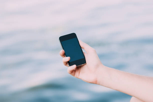 istock Hands holding a smartphone on the street on soft focus background 696436202