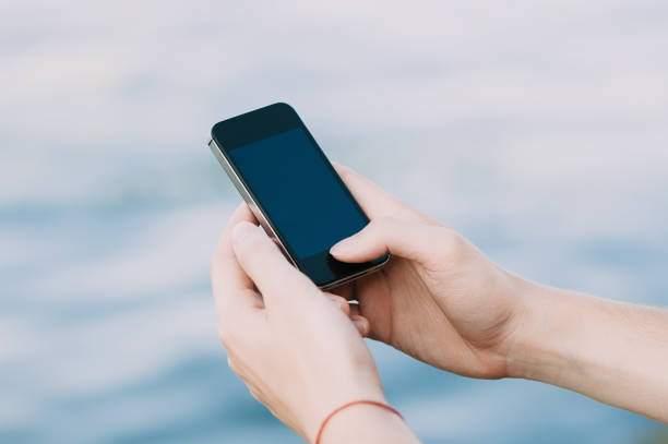 istock Hands holding a smartphone on the street on soft focus background 696436204