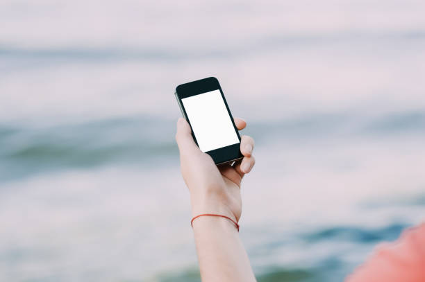 istock Hands holding a smartphone on the street on soft focus background 696436206