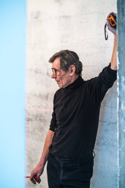 istock 70-years-old active senior man, construction worker - plumber, doing measurments 696436712