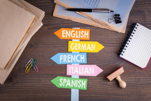 言語の概念、英語、イタリア語、ドイツ語、フランス語、スペイン語。木製の机の上の紙の道標 - 言語 ストックフォトと画像