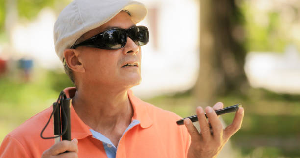 Blind Man Talking With Mobile Phone Disabled Man Speaking"n Hispanic blind man with disability. Visually impaired man using Digital Assistant and Ease of Access functions on mobile phone, voice typing to smartphone assistive technology stock pictures, royalty-free photos & images