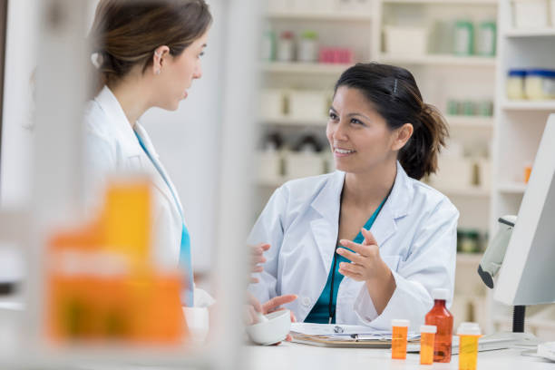 diverse female pharmacists discuss something in the pharmacy - filipino ethnicity asian ethnicity women computer imagens e fotografias de stock