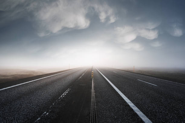Asphalt road leaving in a bright light. Dramatic storm sky in the background