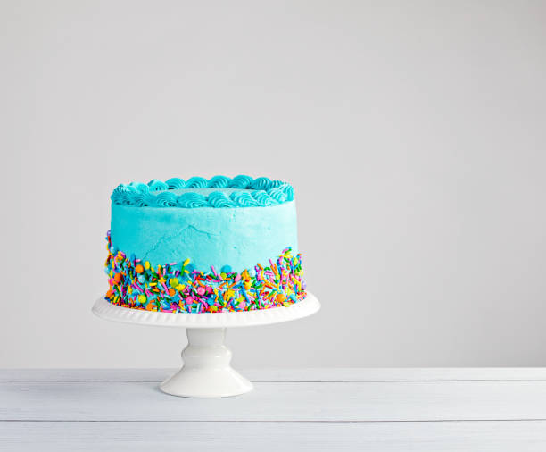 Blue Cake Blue buttercream cake with colorful sprinkles over a light grey background. birthday cake green stock pictures, royalty-free photos & images