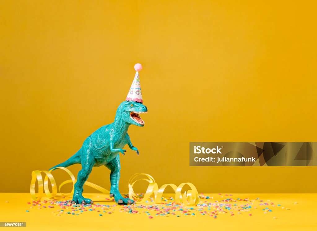 Dinosaur Birthday Party Toy dinosaur with birthday party hat on a yellow background. Dinosaur Stock Photo