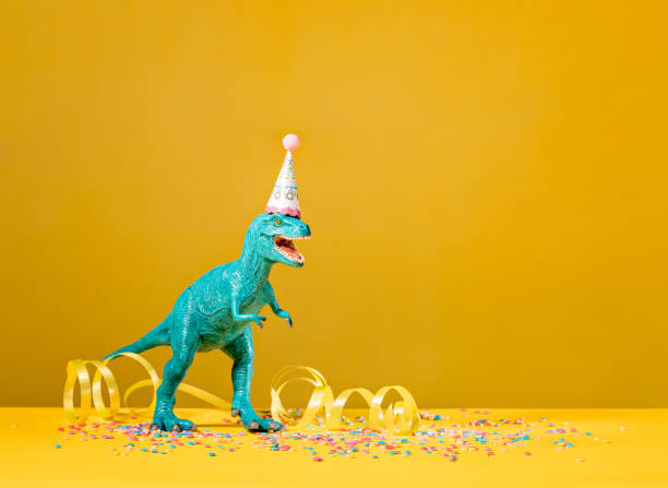 Dinosaur Birthday Party Toy dinosaur with birthday party hat on a yellow background. tyrannosaurus rex photos stock pictures, royalty-free photos & images