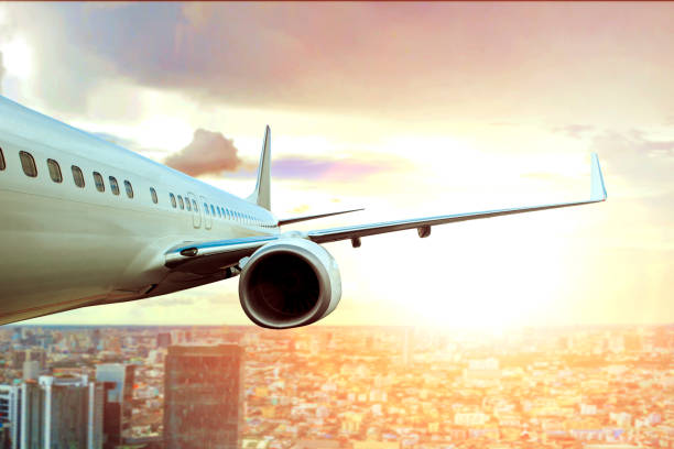 istock passenger plane flying over city building and sun light on background 696471012