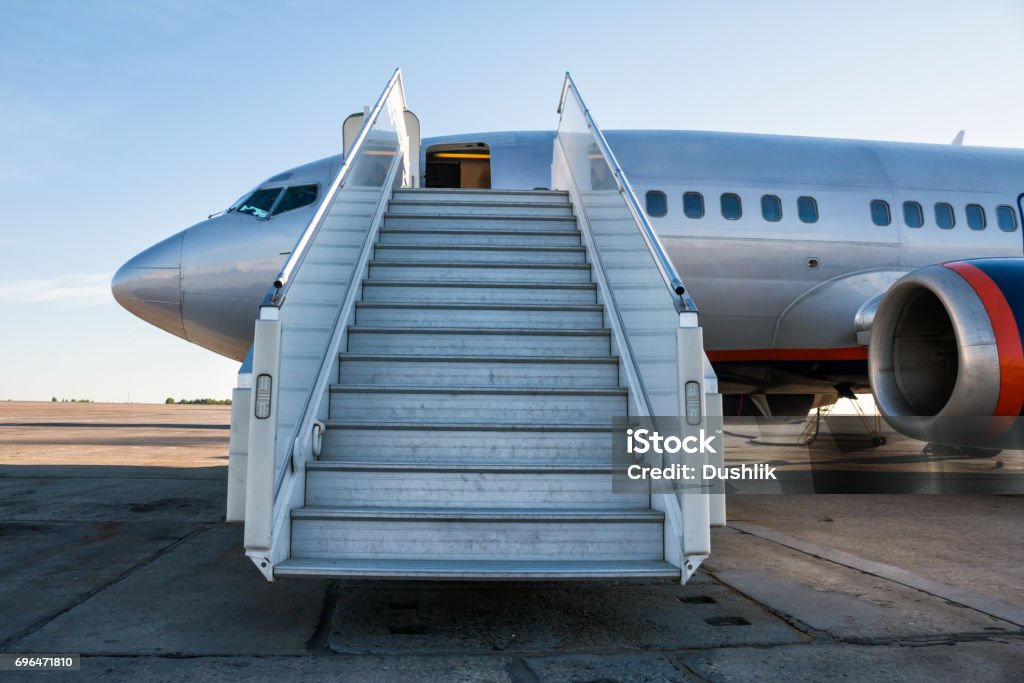 Passenger aircraft with a boarding ramp on the airport apron Aerospace Industry Stock Photo