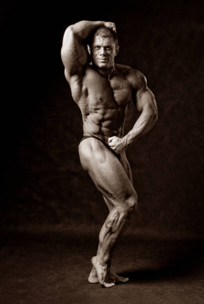 istock Undressed tanned bodybuilder demonstrates his arms and legs muscles 696472016