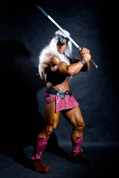 istock Muscular man in an image of a barbarian with a raised sword. 696472128