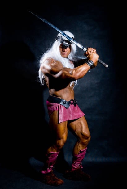 istock Muscular man in an image of a barbarian with a raised sword. 696472132