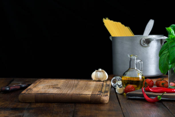 Empty kitchen board with a set of ingredients for cooking Italian pasta on a dark wooden table close up