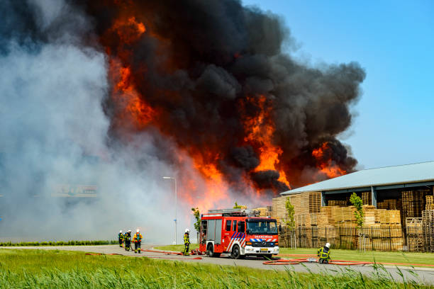 Fire trucks in front of a large fire in a Pallet factory in an industrial area in the city of Kampen, The Netherlands. Fireman are trying to put out the fire.