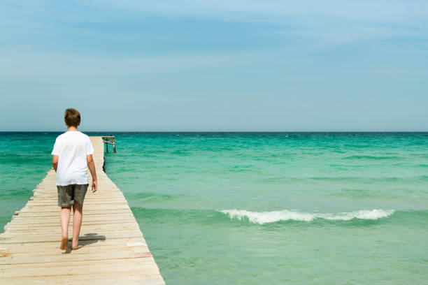 istock Young man walking on a long wood pier 696517538