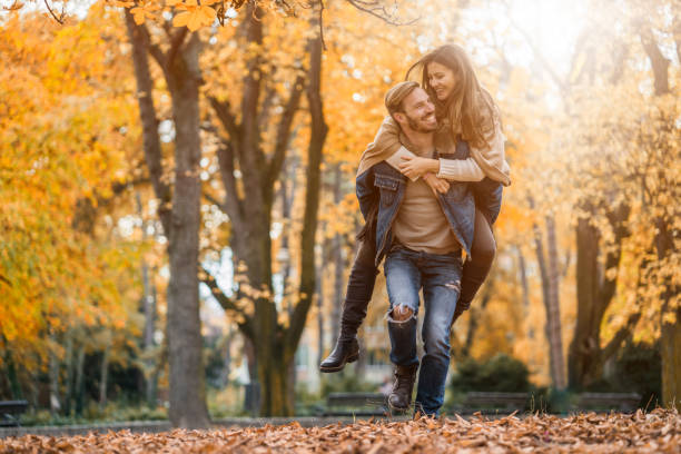 istock Young happy couple having fun while piggybacking in autumn day. 696517694