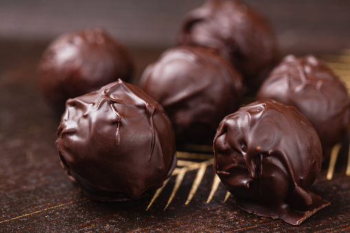 Closeup truffle candies in chocolate on wooden background