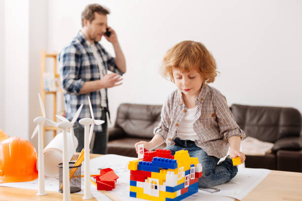 istock Positive delighted child sitting on the table while making toy house 696525924